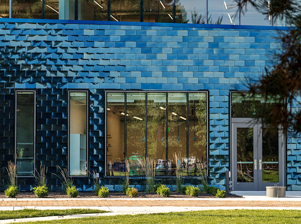 Modern building exterior with blue textured facade, large windows, and glass door entrance